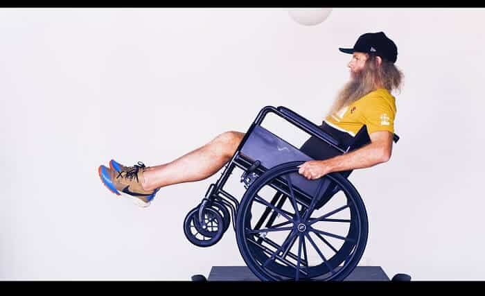Shaun Gladwell balancing a wheel chair on a small dining table